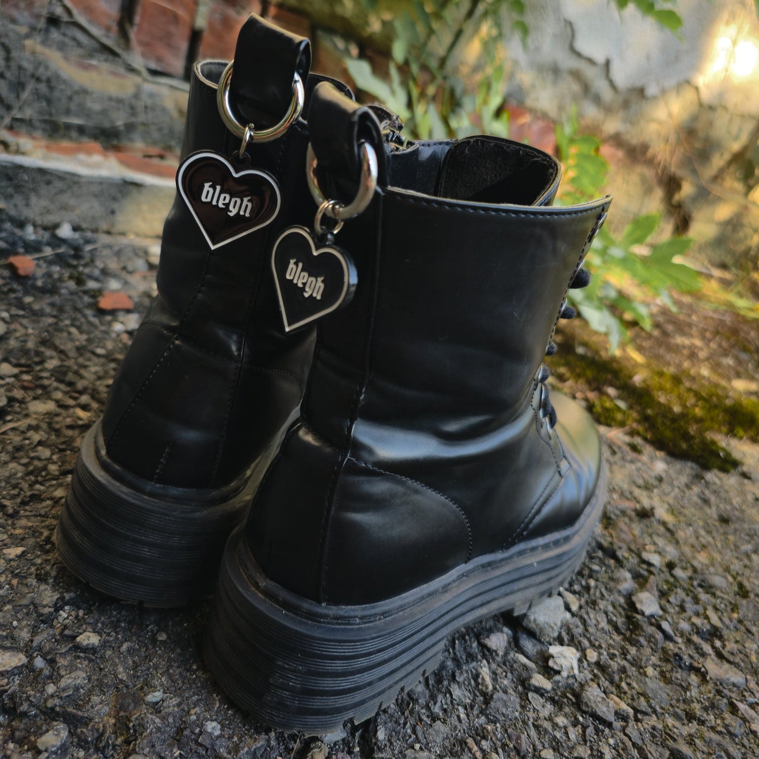 Schwarzer Boot Charm in Herzform mit weißer Umrandung und dem Wort „blegh“, befestigt an einem silbernen Karabiner für die Zuglasche von Stiefeln.