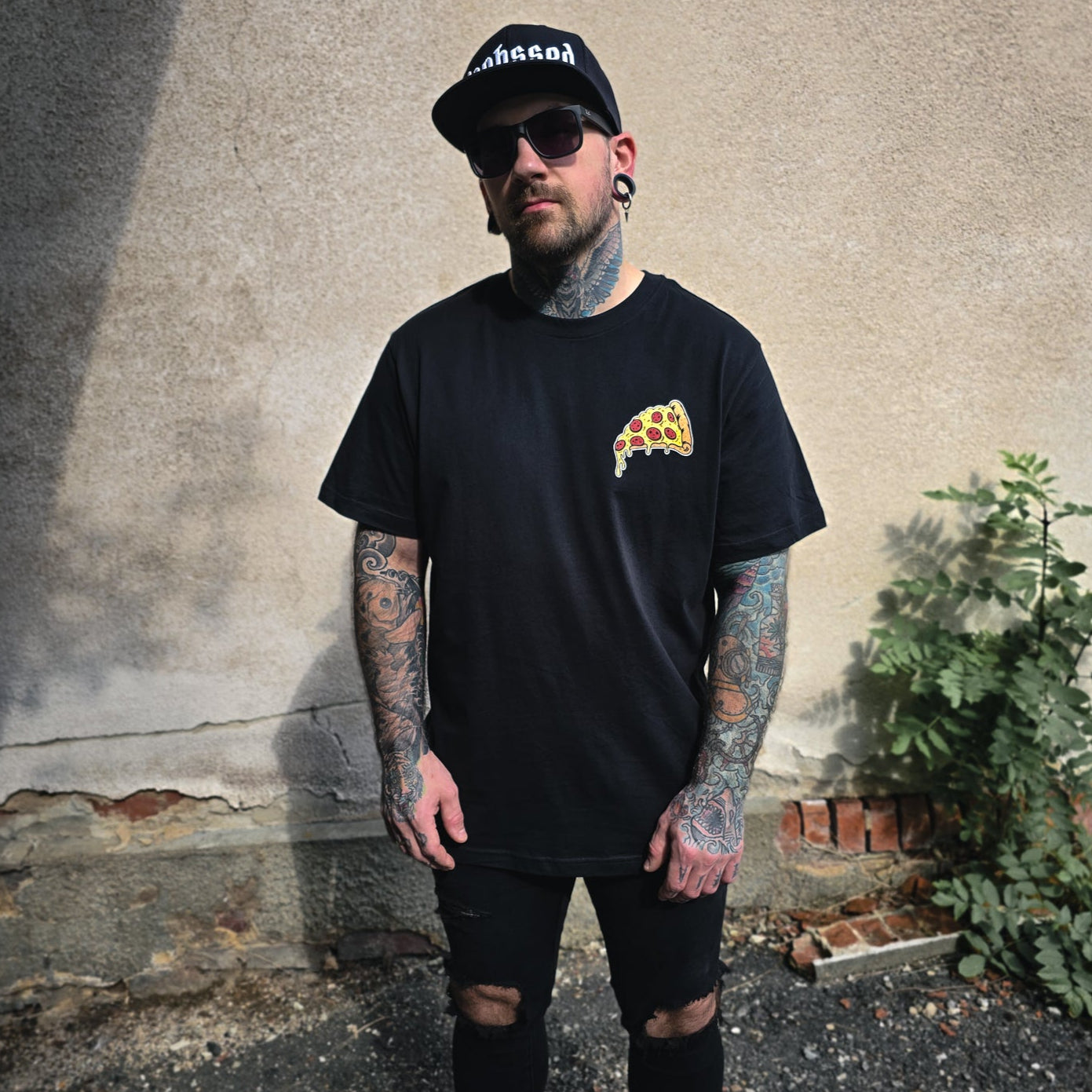 Schwarzes Shirt mit kleinem Pizzastück als Brustprint auf der Vorderseite.