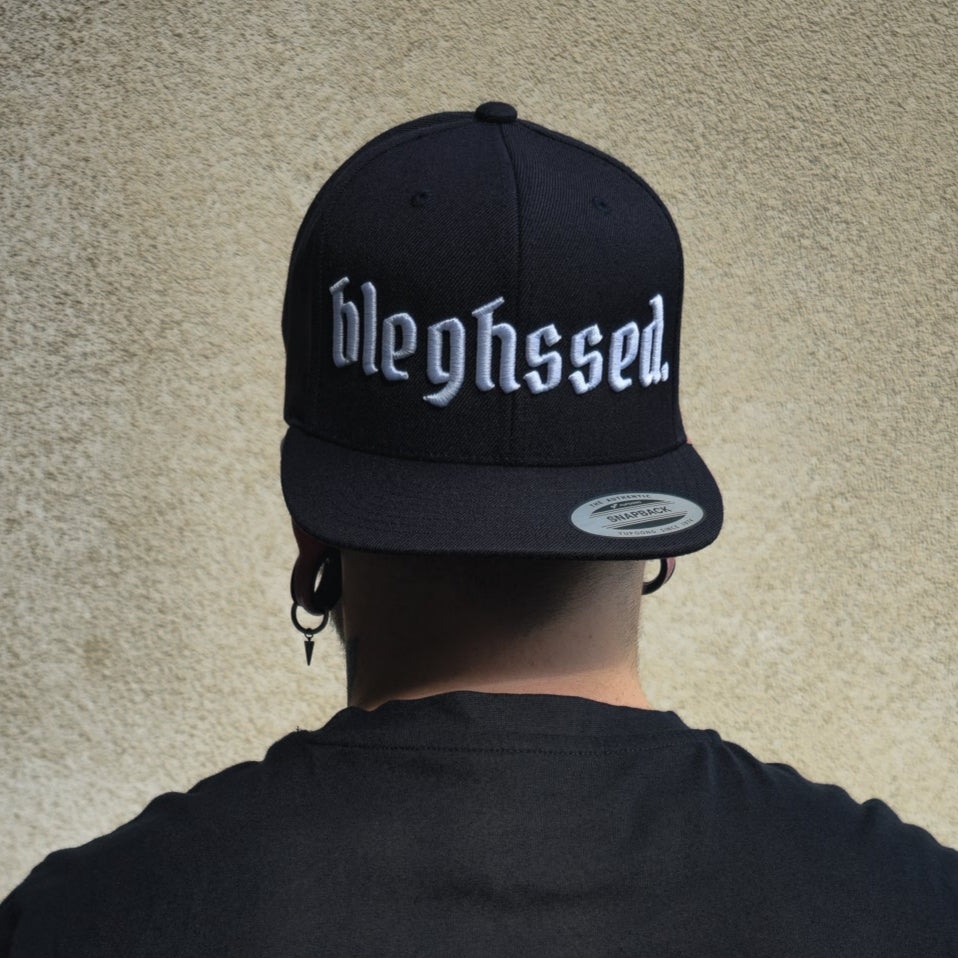 Schwarze Cap mit weißer 3D-Stickerei des Schriftzugs ‚bleghssed‘ auf der Vorderseite